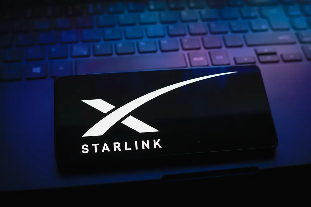 The Starlink logo is displayed on the screen of a smartphone.